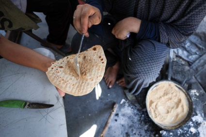 Sabrine Toushtash serves dukkah to her child inside a tent shelter, amid food scarcity and a hunger crisis, in Gaza City