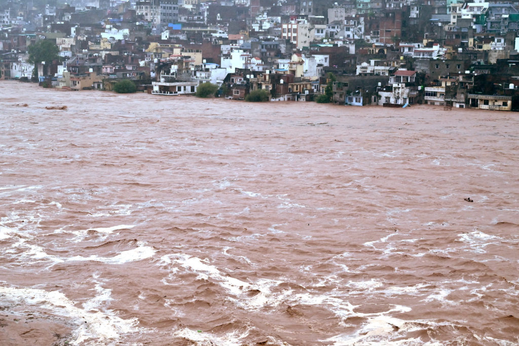 Water flows down the overflowing Tawi River following heavy rainfall in Jammu