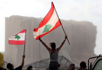 Demonstrators wave Lebanese flags during protests near the site of a blast at Beirut's port area