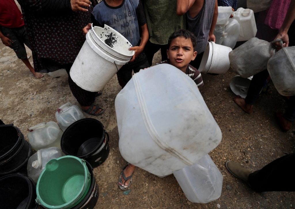 Displaced Palestinians fill water containers at a tent camp, in Gaza City