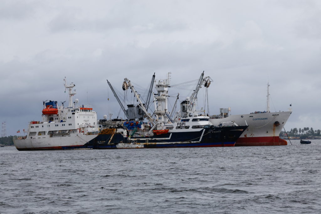 A tuna fishing vessel unloads its cargo onto another boat at a quay in the port of Abidjan