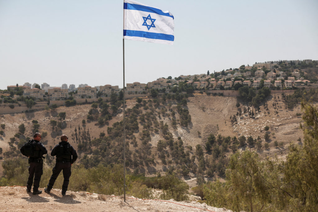 FILE PHOTO: Israeli flag flutters, as part of the Israeli settlement of Maale Adumim is visible in the background, in the ...