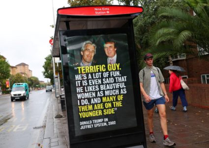 People walk past a poster with a photograph of Donald Trump, now serving as the U.S. President, and disgraced financier an...