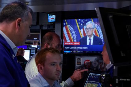 Traders work, as a screen broadcasts a news conference by U.S. Federal Reserve Chair Jerome Powell as traders work on the ...