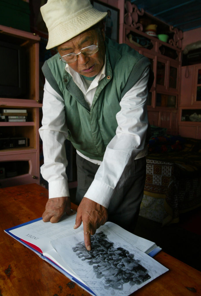 KANCHA NURU SHERPA POINTS AT AN OLD PHOTOGRAPH SHOWING HIMSELF BETWEEN MEMBERS OF THE MOUNT EVEREST ...