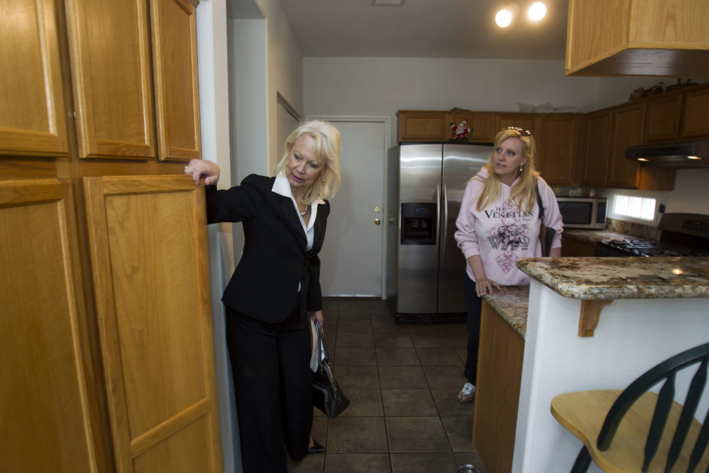 Reality Executives owner/broker Moore and realtor Riley look at kitchen cabinets of a home for sale in Henderson