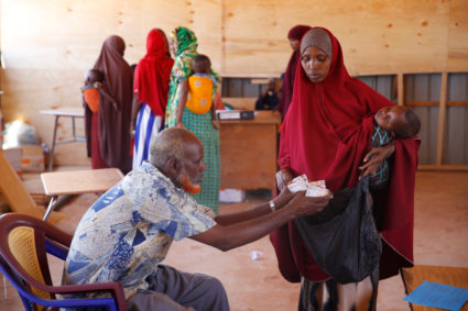 A Somali woman holds her baby as she receives infants food aid in the northern Somali town of Dollow