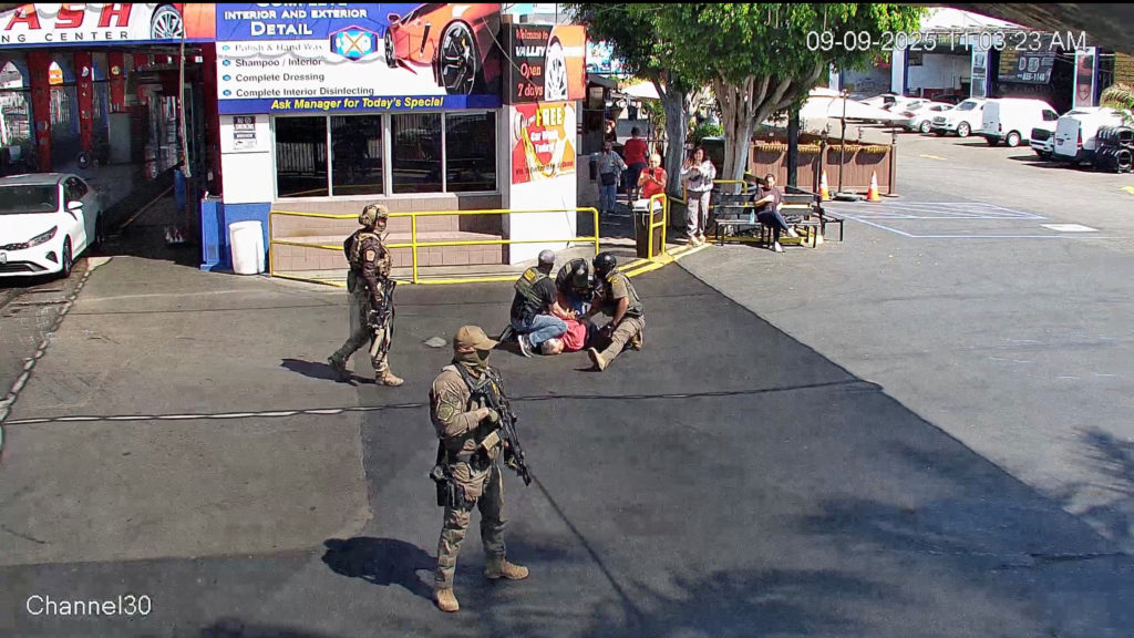 Car wash owner is held down by security forces members during a raid, in Van Nuys