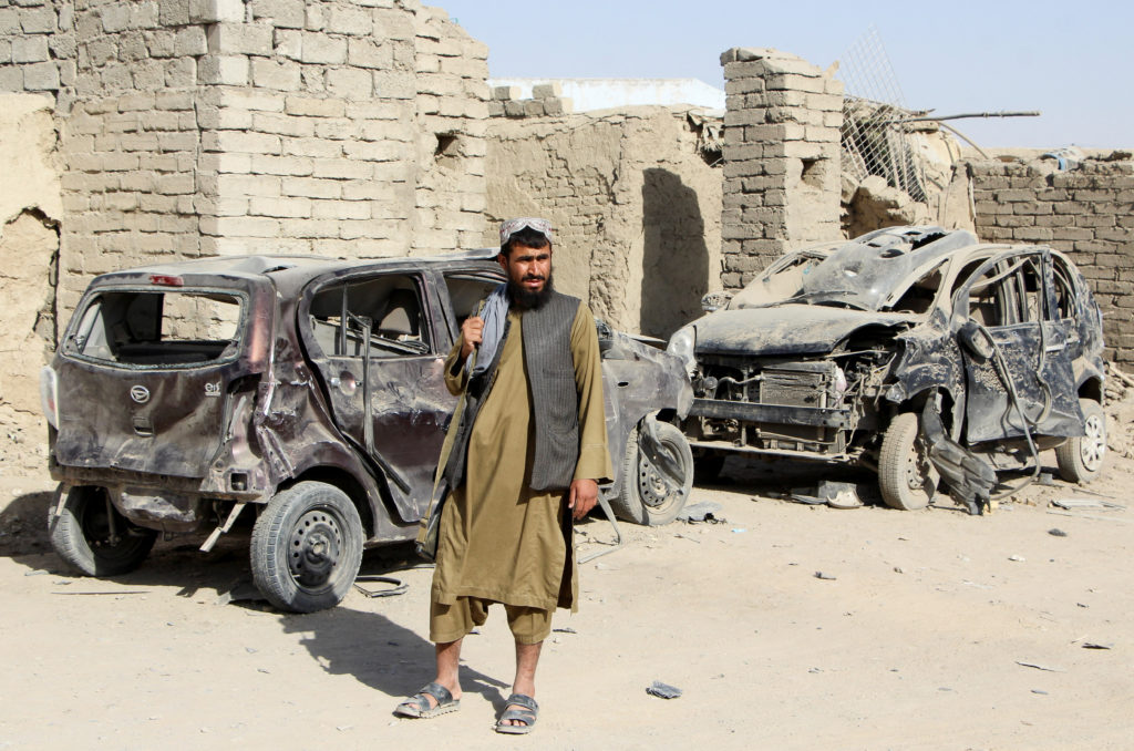 A Taliban fighter stands next to vehicles destroyed during an airstrike following a temporary ceasefire amid the conflict ...