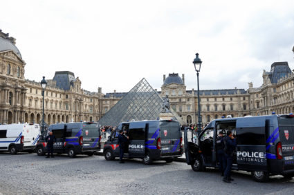 French police vans are parked near the glass Pyramid of the Louvre Museum