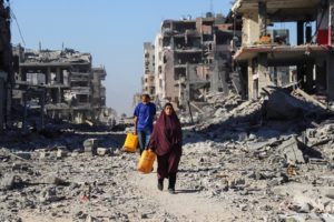 Palestinians walk past the rubble of destroyed buildings, amid a ceasefire between Israel and Hamas, in Gaza City