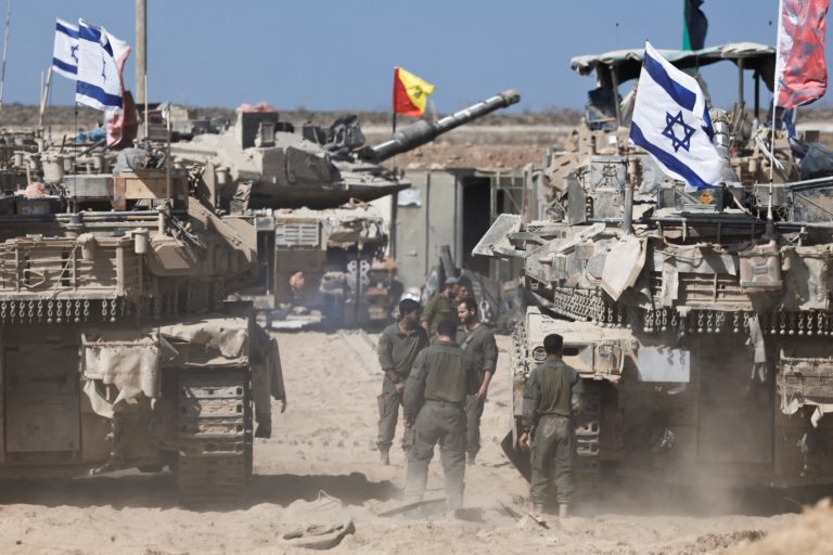 Israeli soldiers stand next to tanks near the Israel-Gaza border, in Israel