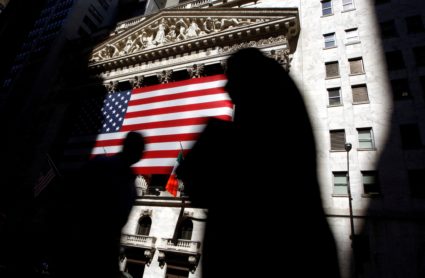 FILE PHOTO: The sun lights the exterior of the New York Stock Exchange, as people walk past on the shadowed street
