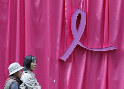 Visitors walk past a sculpture of a pink ribbon installed to promote the "Pink Ribbon" breast cancer awareness campaign at...