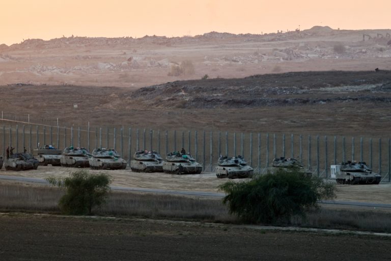 Israeli military vehicles stand on the Israeli side of the border with Gaza