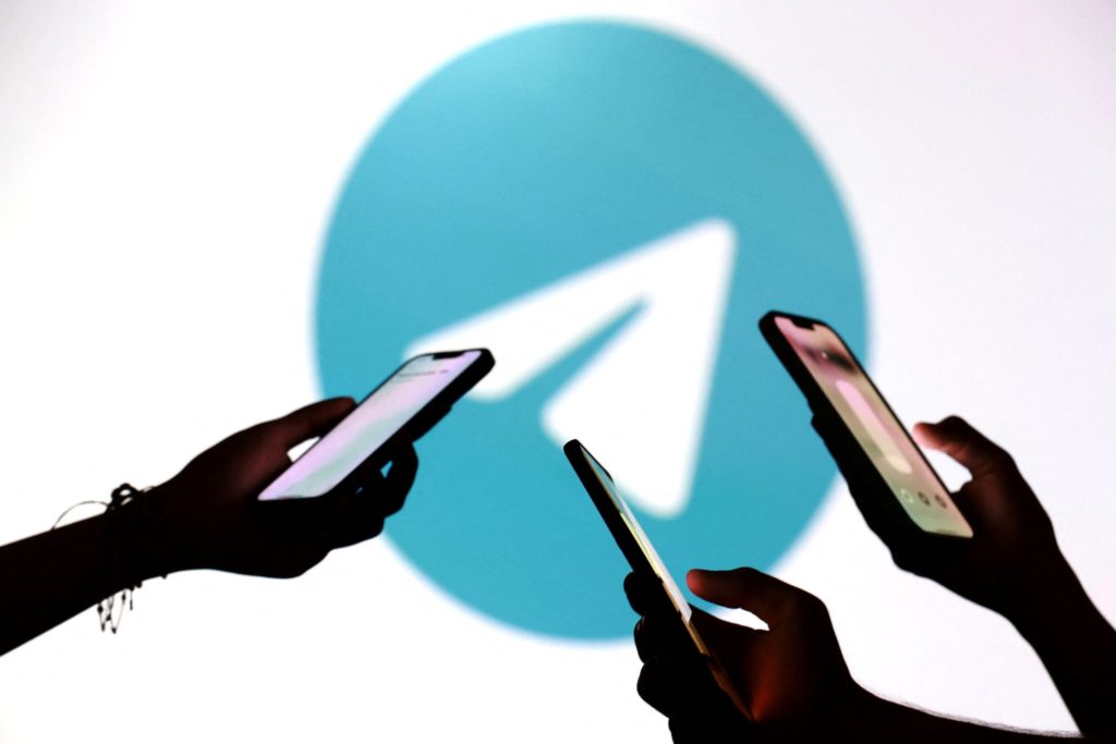Illustration shows teenagers pose for a photo while holding smartphones in front of a Telegram logo