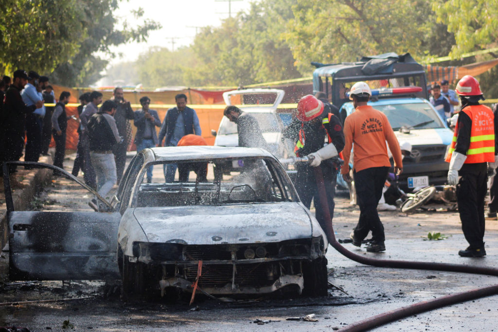 Firefighter douses a vehicle after a blast outside a court building in Islamabad