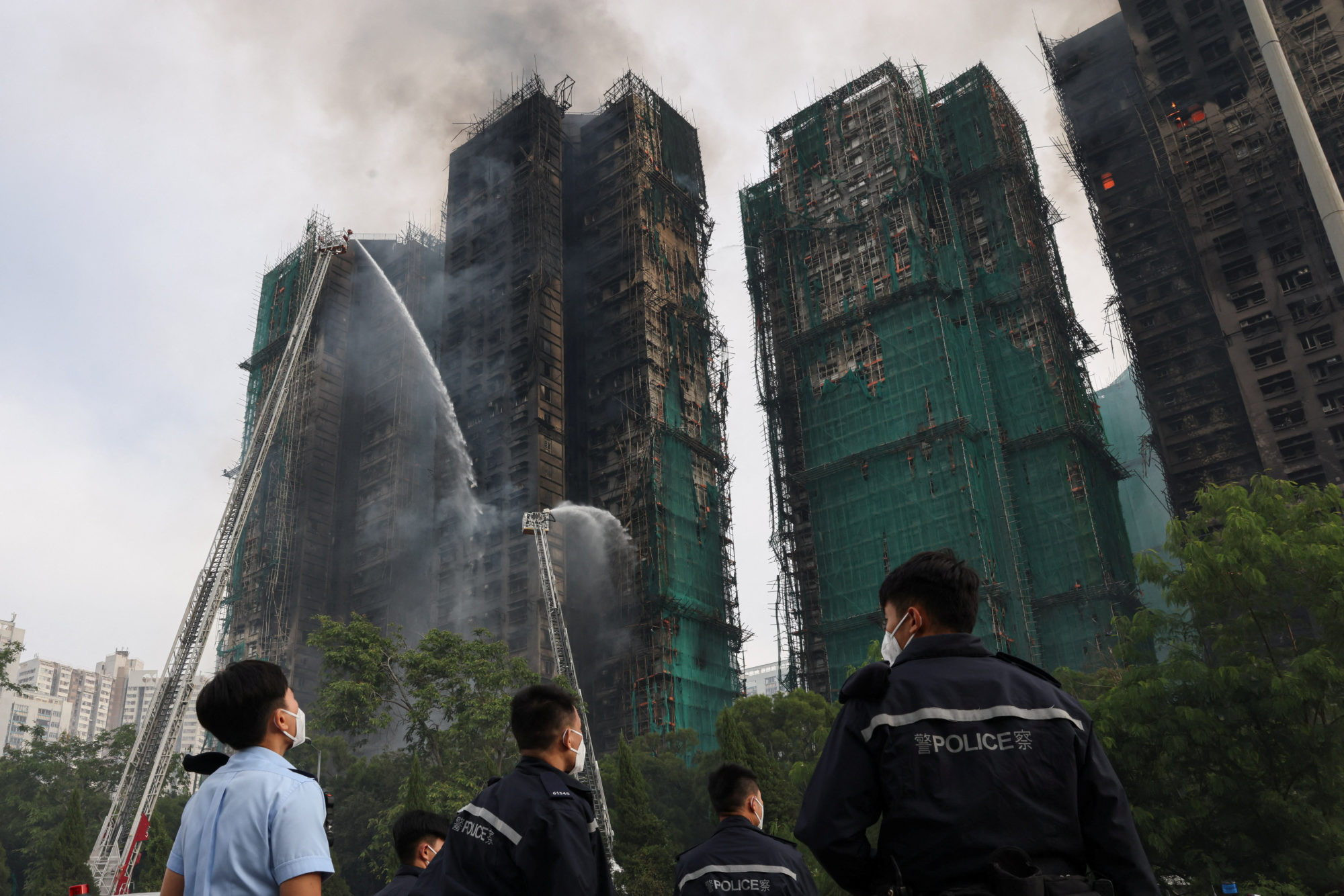 Police stand guard at the scene of a major fire at Wang Fuk Court housing estate, where flames engulfed bamboo scaffolding...