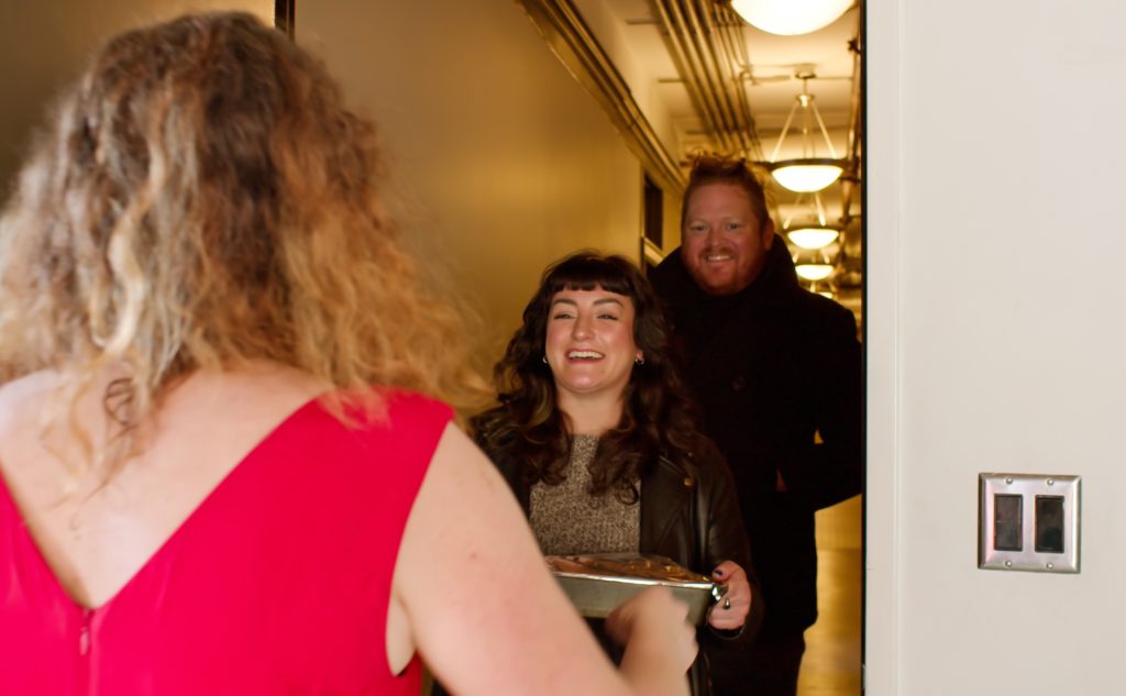 Woman Welcoming Guests to Friendsgiving Potluck
