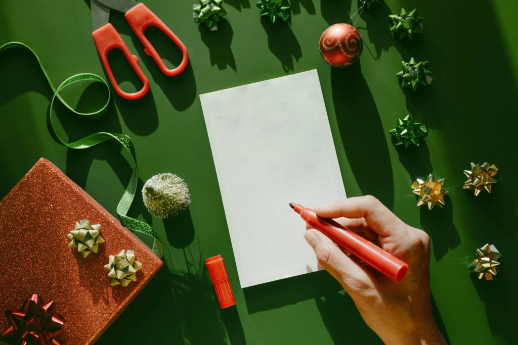 Blue notebook with a sheet of paper and a pen in female hand on green background