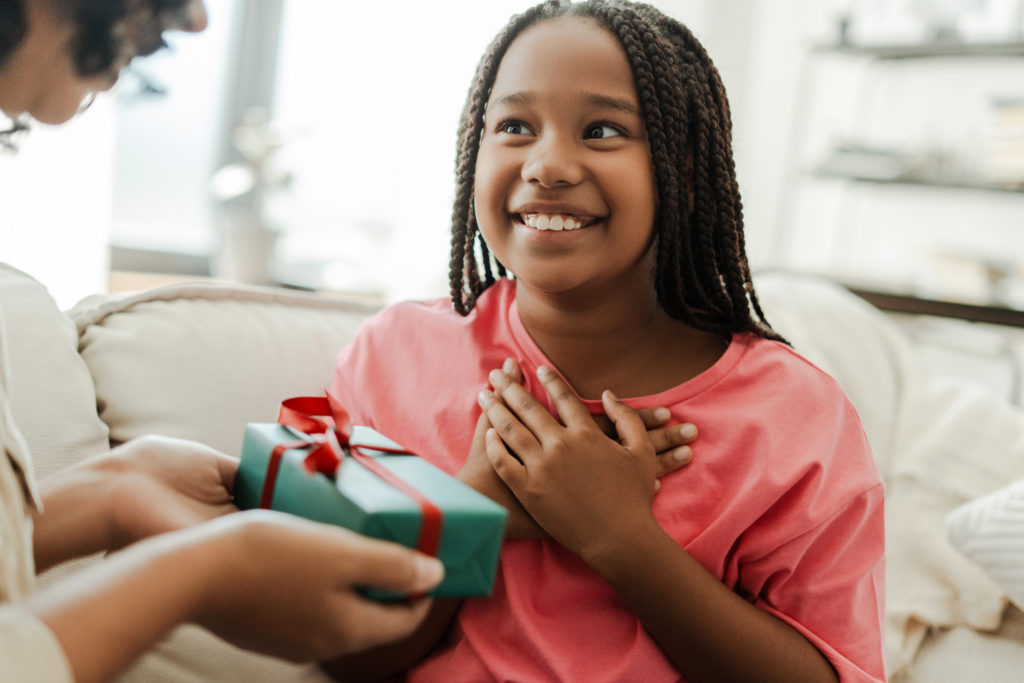 Excited girl receiving a gift from her mother at home