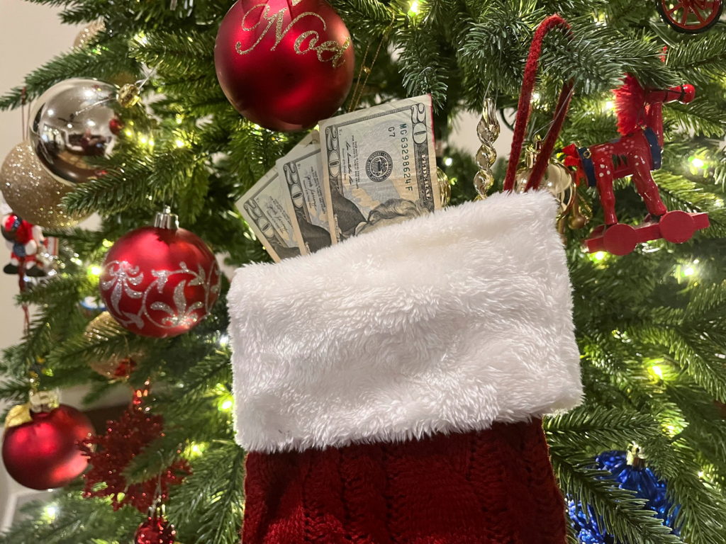 A photo illustration shows a stocking with 20 dollar bills hanging on a Christmas tree