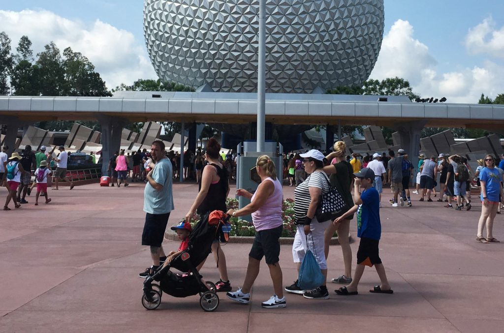 Visitors walk pass a Stars and Stripes flying half-staff at the entrance to the Epcot Center at Walt Disney World resort i...