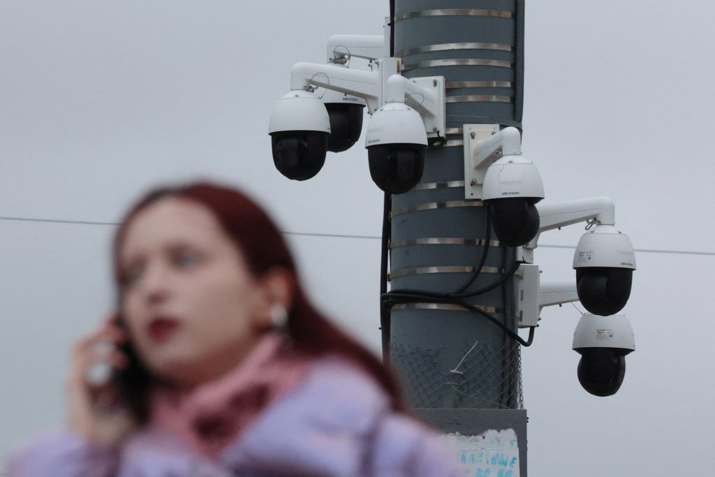 A woman talks on the phone with surveillance cameras in the background in Saint Petersburg
