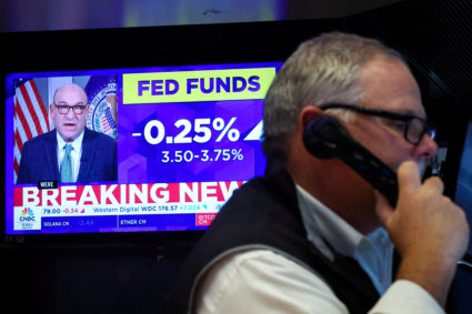 A screen displays the Fed rate announcement as traders work on the floor of the NYSE in New York