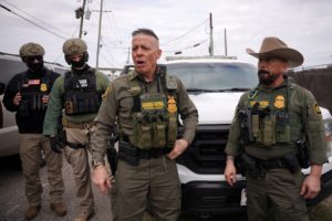 Border Patrol commander Greg Bovino and Border Patrol agents stand on a side street in Kenner