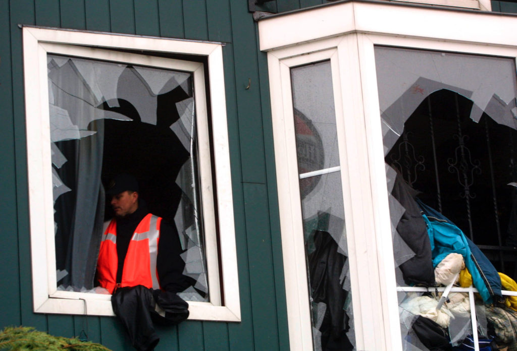 A POLICE MAN LOOKS AWAY FROM A BROKEN WINDOW OF THE BURNED OUT DISCO IN VOLENDAM.