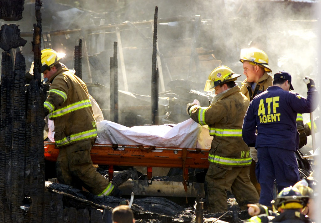 Firefighters carry the remains of a victim through the burnt wreckage of "The Station" nightclub Feb..