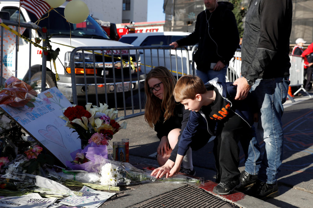 Two children place flowers at a makeshift memorial near the scene of the fatal warehouse fire in Oakland, California