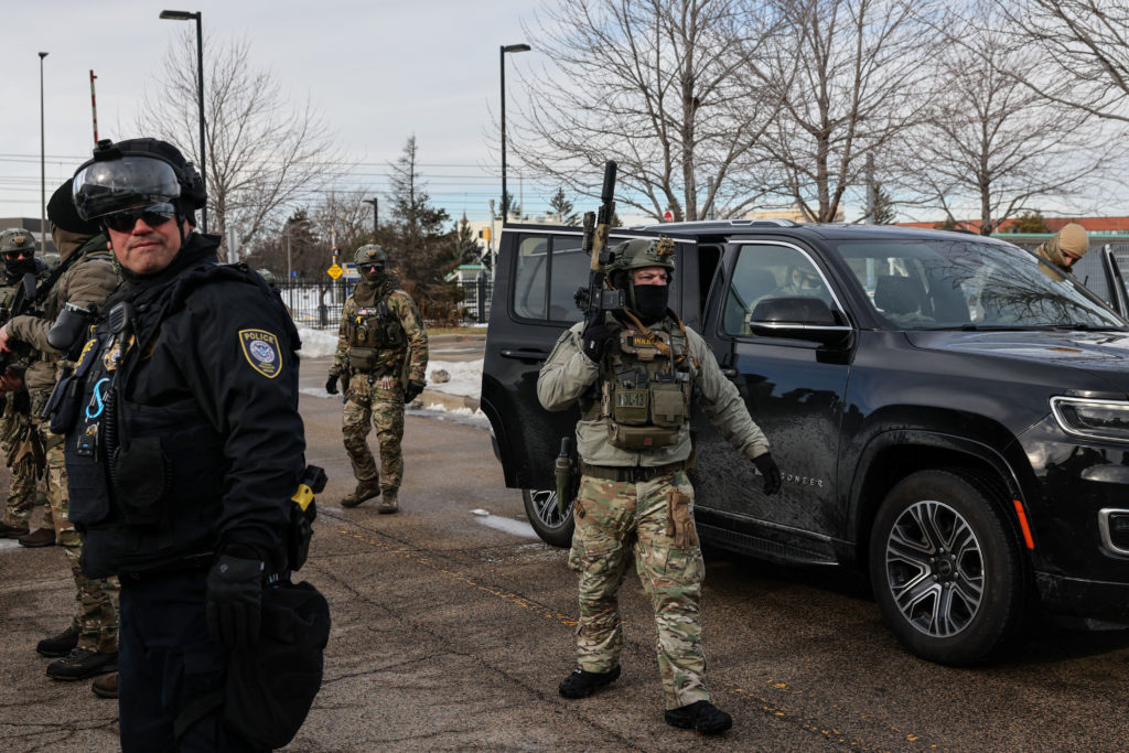An ICE vehicle is blocked by demonstrators outside the Bishop Henry Whipple Federal Building during a protest against incr...