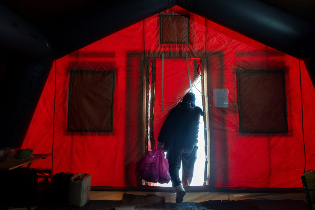 People warm up in a tent provided by emergency services for residents whose apartments are left without heating in Kyiv