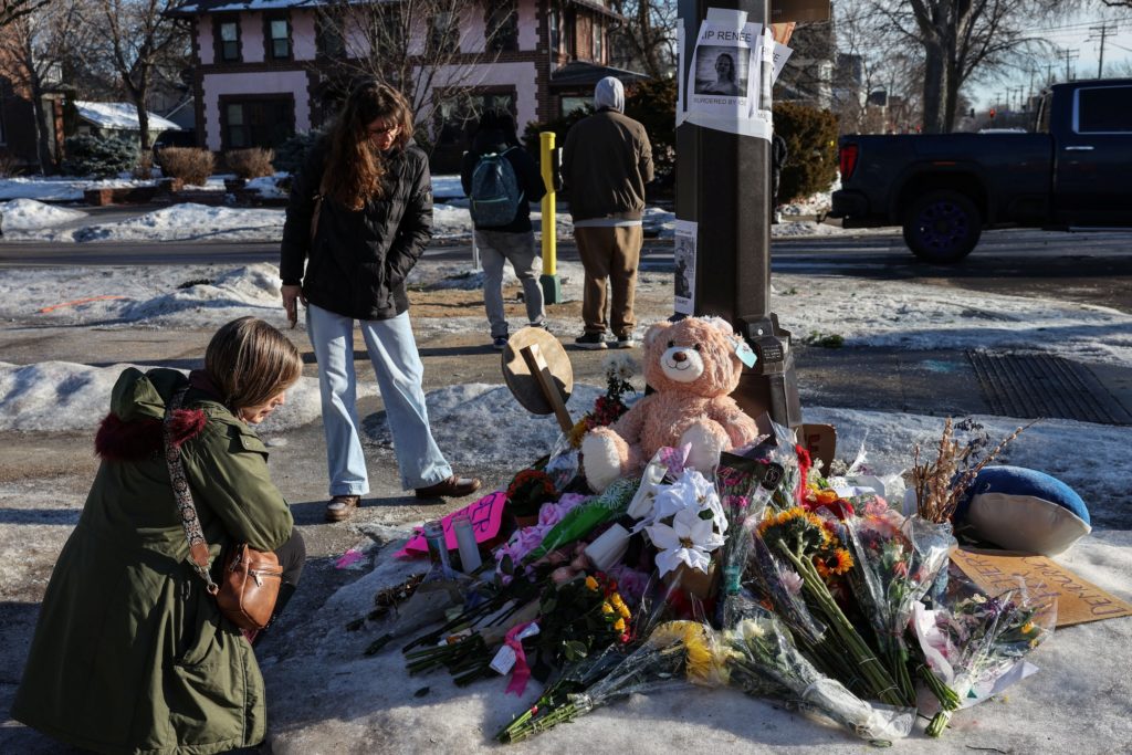 People stand by a makeshift memorial at the scene of the fatal shooting of Renee Nicole Good by a U.S. Immigration and Cus...