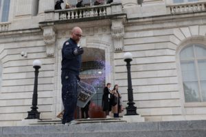 A worker throws salt on the steps of the Cannon House Office Building in preparation for a snowstorm, in Washington