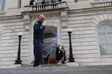 A worker throws salt on the steps of the Cannon House Office Building in preparation for a snowstorm, in Washington
