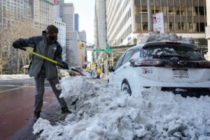 A person cleans snow from their vehicle in New York City