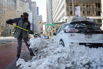 A person cleans snow from their vehicle in New York City