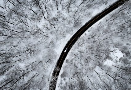 A drone view of a car driving through the snow covered woods of Blauvelt State Park after a winter storm bore down on the ...