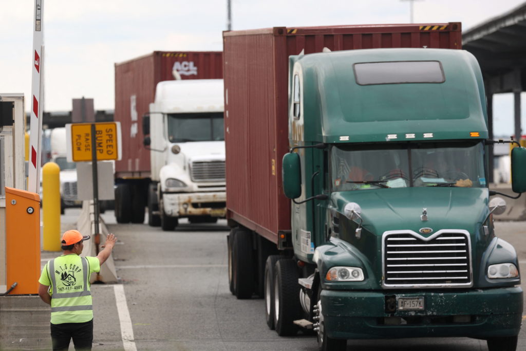 A worker directs traffic after trucks are loaded, in Newark