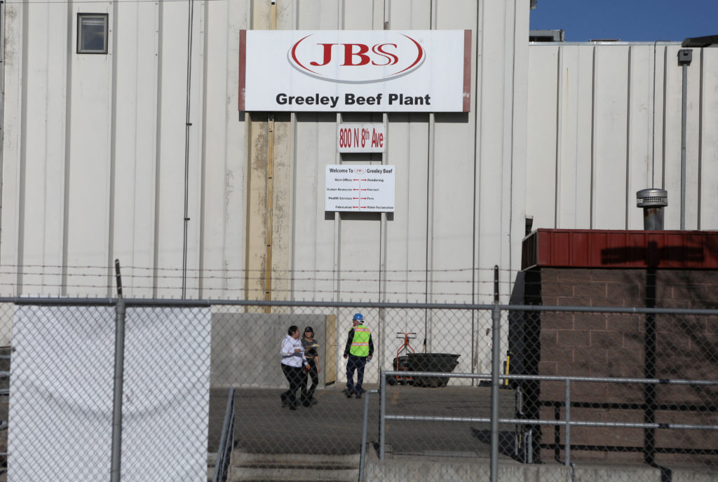 FILE PHOTO: Employees walk around without face mask at the JBS USA meat packing plant in Greeley