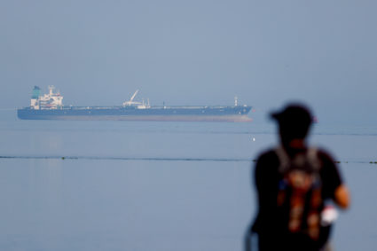 A tourist watches the MT Desert Kite oil tanker carrying Russian oil at Narara Marine National Park in the Arabian Sea