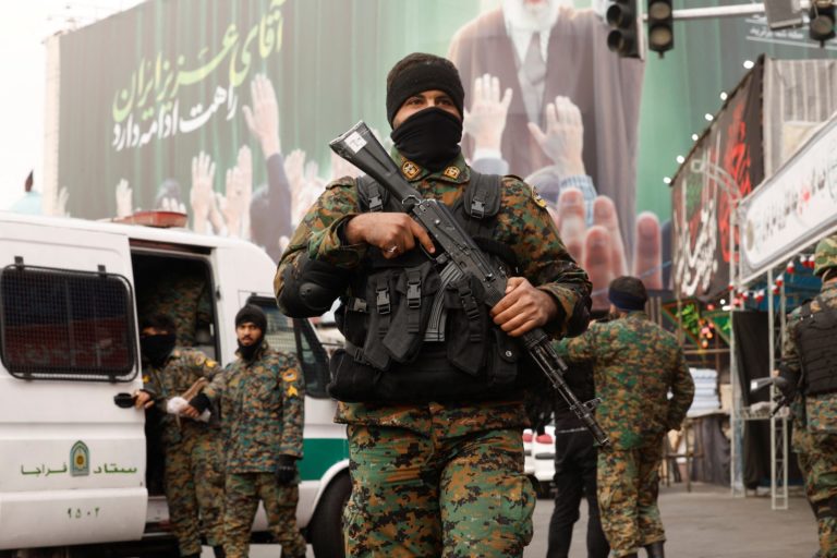 Members of the police stand guard on a street, with a large billboard featuring Iran's late Supreme Leader Ayatollah Ali K...