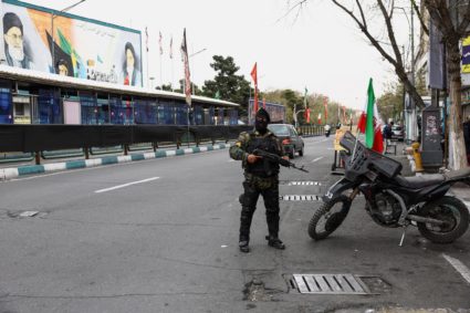 A member of a police force stands guard on a street, amid the U.S.-Israeli conflict with Iran, in Tehran