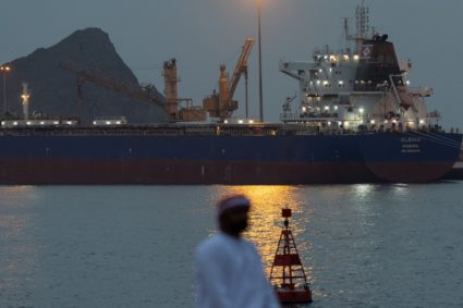 A man sits on the waterfront as vessel sits at anchor inside Sultan Qaboos Port in Muscat