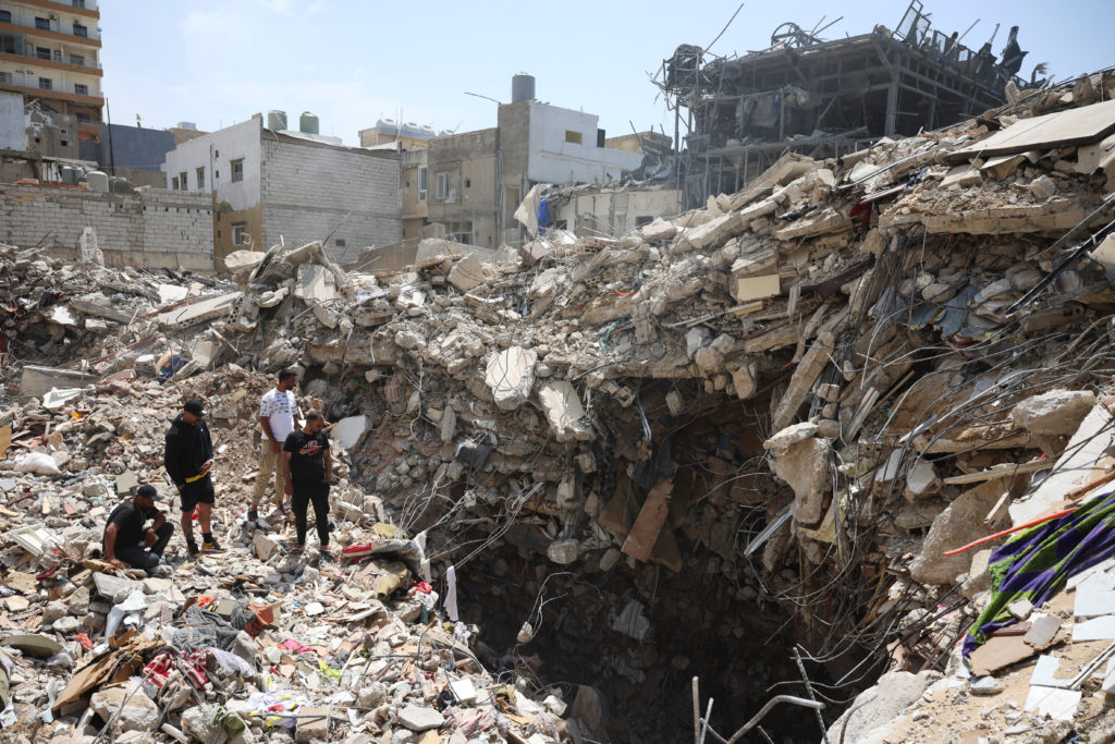 People gather at the site of an Israeli strike carried out before a 10-day ceasefire between Lebanon and Israel went into ...