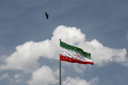 A bird flies over an Iranian flag in Tehran