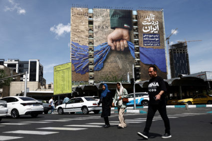 People walk past a billboard with a graphic design about the Strait of Hormuz on a building, in Tehran